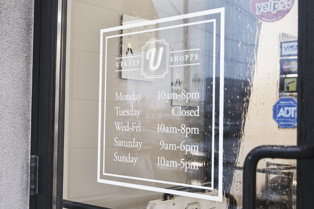 Cut vinyl signage for The Upkeep Shoppe on Preston St in Ottawa, ON. Logo, business hours, and sidewalk sandwich board graphics.